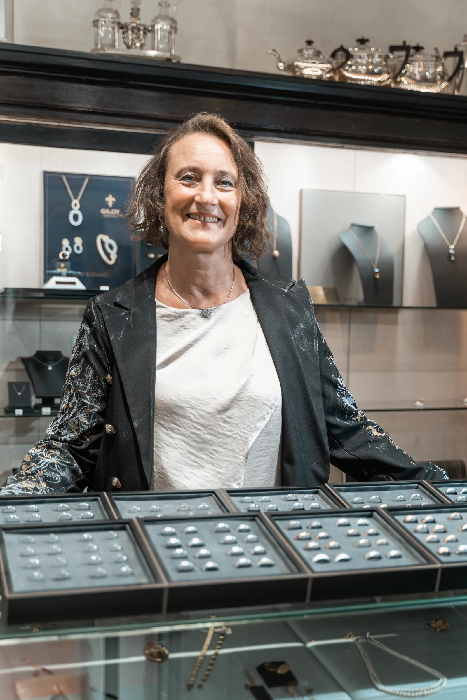 Renate Winkler lacht hinter der Ringvitrine in ihrem Geschäft